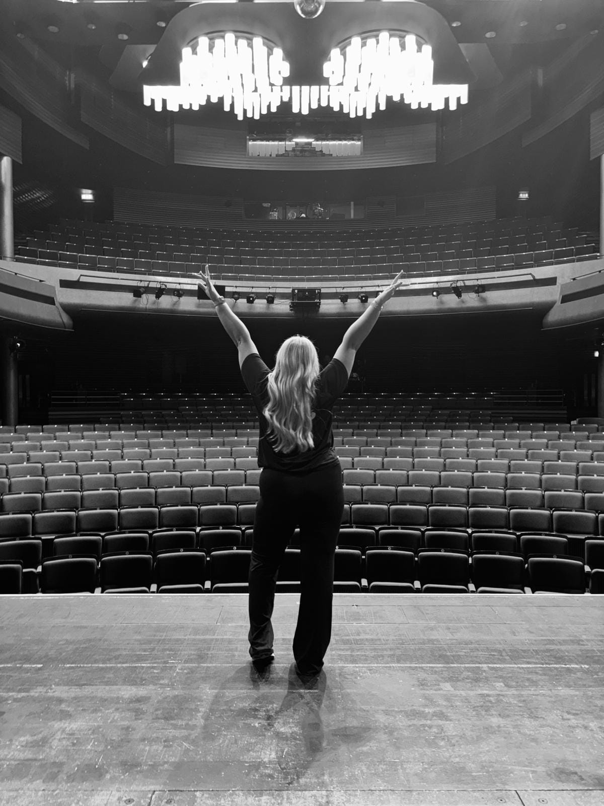 Dancer on stage facing an empty theatre